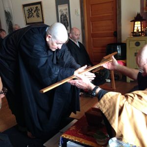 Kuya receiving a kyosaku, a stick traditionally used to tap meditators to help them stay alert, during the ordination ceremony.