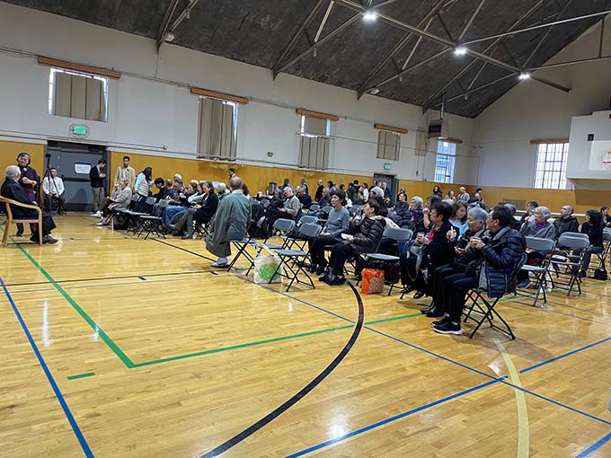In November, Reverend Kusunoki, back to camera, encourages coffee socializers to be seated for Dharma Exchange. The open gymnasium setting encouraged connection between attendees.