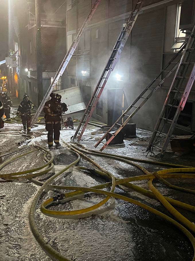 Firefighters battling the  second  blaze on Jan. 1, 2024, from the alley behind the  temple.