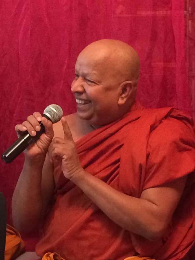 Ven. Pagnananda shares a joyful moment while addressing the community, reflecting the warmth, humor, and approachability remembered by his devotees