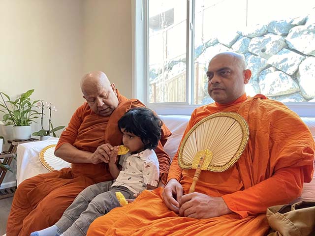 Ven. Pagnananda sits with a young child and fellow monk, showing the close relationship between the Sangha and families at the Tukwila temple