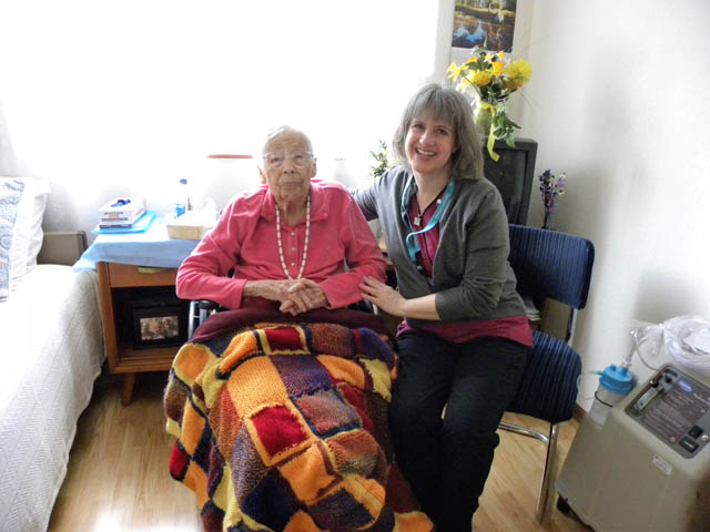 Volunteer Julia Guderian with patient Roberta M, warmed by a blanket that Guderian’s son’s class knit for this hospice patient.