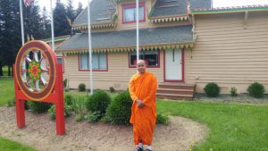 Ven. Aggashri  in front of the current building, which features a dharma wheel