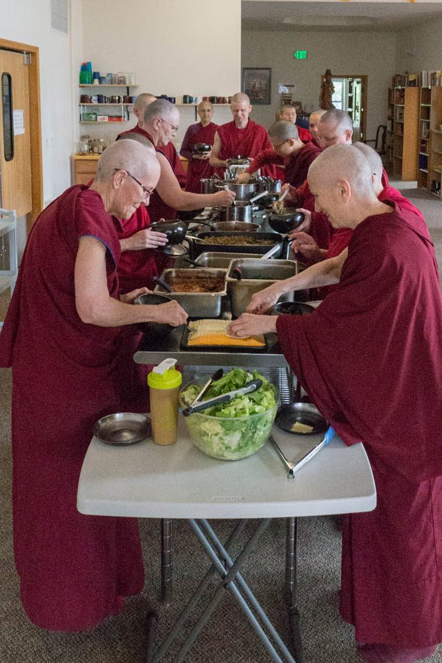 Abbey monastics approach the food serving line in ordination order. Author Ven. Thubten Chodron (right), who is the founder and abbess of Sravasti Abbey, leads the way