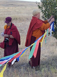 Ven. Khenpo Lama Karma Namgyel Rinpoche American nun Katrina Pruette hang prayer flags on the retreat land, to send prayers of healing in all directions