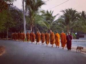 Monks in Thailand must walk for alms each day, which keeps them engaged with the surrounding community