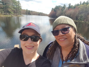 Rachel Lewis and Tuere Sala relax in the sunshine alongside Gaston Pond, near Insight Meditation Society