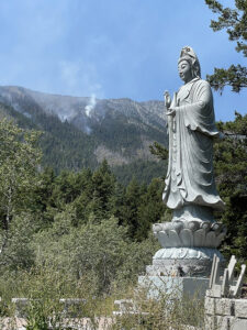 The Lions Gate Buddhist Priory Kwan Yin statue, with spot fires still burning on the mountain