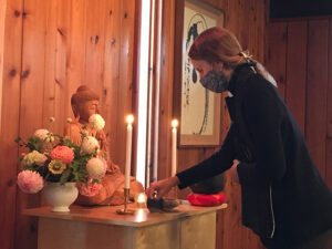 Myoshin Elizabeth Fritterer lights candles at the meditation hall altar, during the blessing ceremony