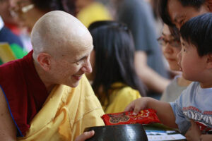 Ven. Thubten Chodron receives a child’s offering during an alms round with monastics from a temple in Jakarta, Indonesia