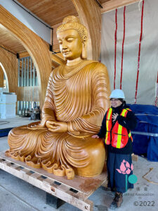 Venerable Yin Kit with the 10-foot cedar statue of the Buddha, minutes after installation in spring, 2021