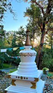 Morning sunrise by the stupa, with Tibetan prayer flags among the trees
