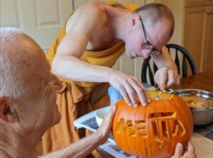 Thanissaro Bhikkhu and Taan Mike carving a metta jack-o'-lantern