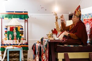 Rabjam Rinpoche and Tulku Sangak Rinpoche throw flowers during a ritual in the meditation hall