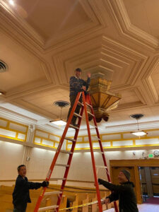 Reverend Katsuya Kusunoki examines the diamond-shaped ceiling lantern in the main hall, while volunteers assist