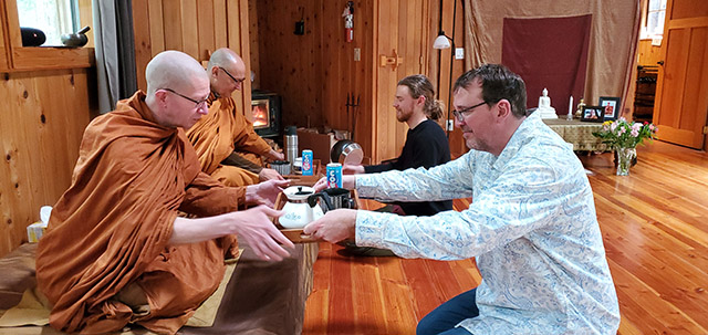 Lay supporters Mark Schmidt and Sam Tuck (L to R) offering trays of evening allowables to monastics Taan Will and Ajaan Peter