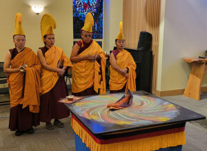 The nuns chant over the swirl of color left by the dissolution of the mandala