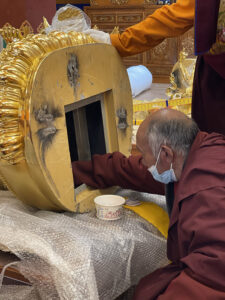 Consecrating a statue at the shedra, by inserting mantra scrolls and relics in the bottom