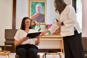 Sakula offers Swanson her lay minister commissioning certificate, as a symbol of their leadership transition