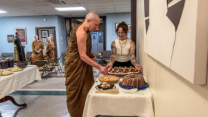 Soren High offers the meal to Tan Dhammavaro in traditional Thai forest tradition style. In the background elder monks Luang Por Pasanno and Ajahn Sudanto, converse with No Rank Zendo’s Rinzan Pechovnik Osho