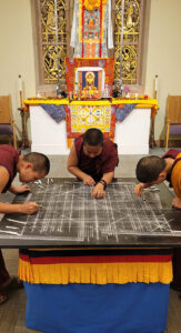 Chung Dolma (left), Sonam Dolma (middle), and Sherab Dolma (right) meticulously measure out and draw the geometric patterns of the mandala, during the sand mandala ceremony at  the church