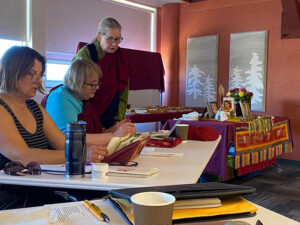 Hannah Engasser, Vickey Aschacher, and Cheryl Buchan doing a 2024 tsog, a traditional and complex offering practice, to the meditational deity Chenrezig